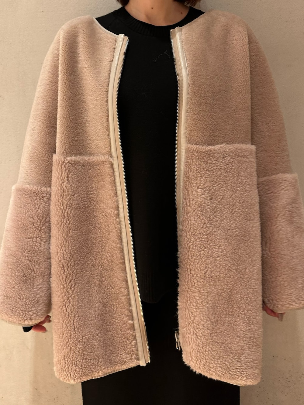 ブラック系のスカート、ブラック系のブーツ、ベージュ系のノーカラーコートを着用したレディースの夏コーディネートの5枚目の写真