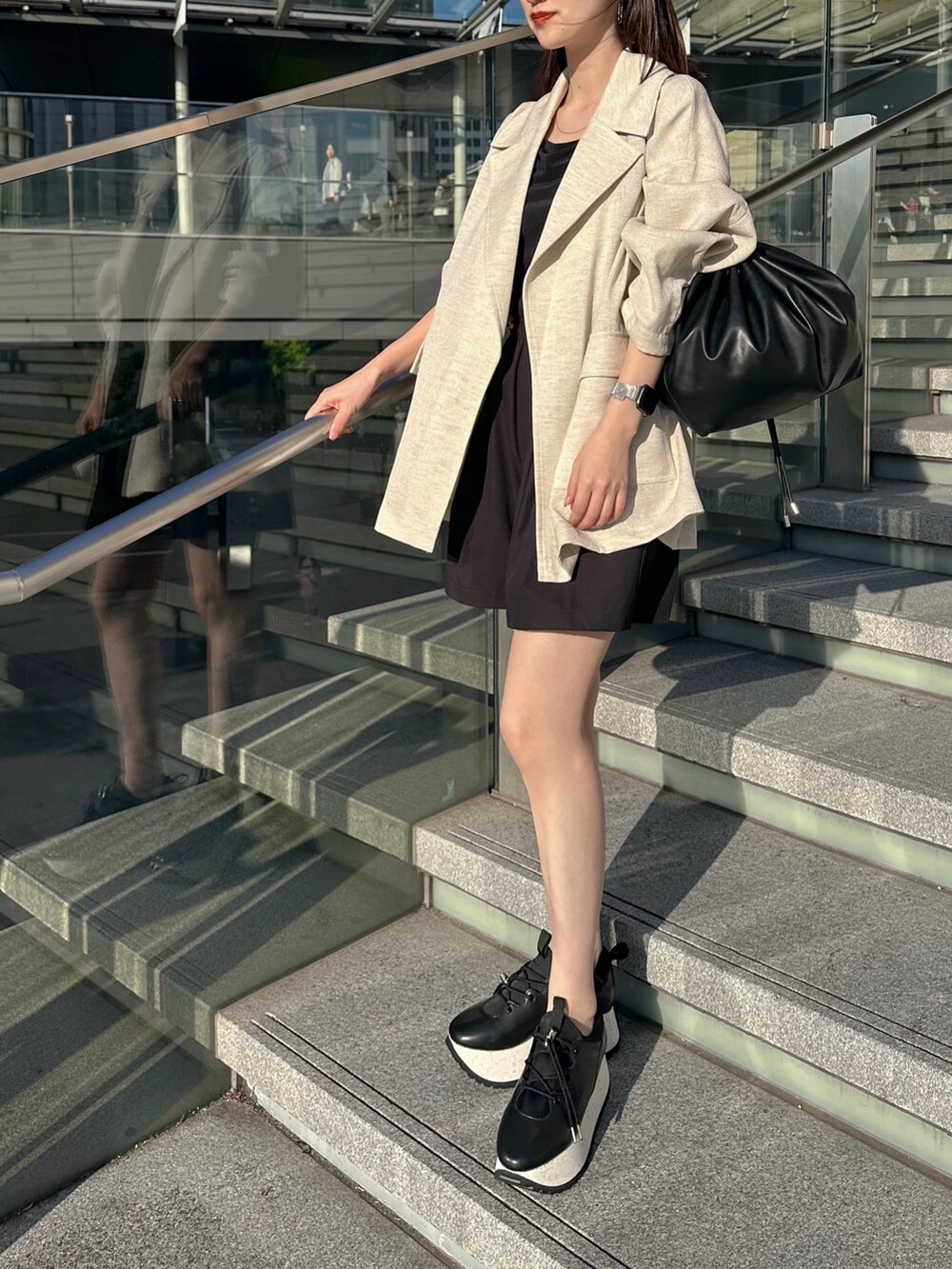 ブラック系のキャミソール、ベージュ系のテーラードジャケット、ブラック系のショルダーバッグを着用したレディースの春コーディネートの5枚目の写真