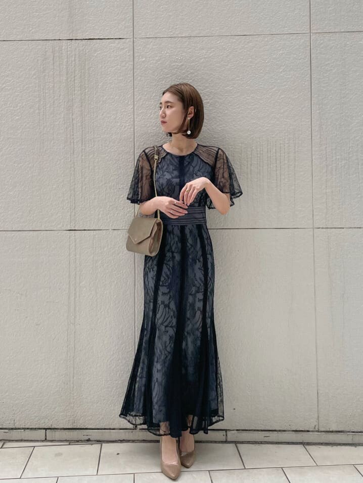 ゴールド系のパンプス、ゴールド系のクラッチバッグ、ブラック系のドレスを着用したレディースの春コーディネートの2枚目の写真