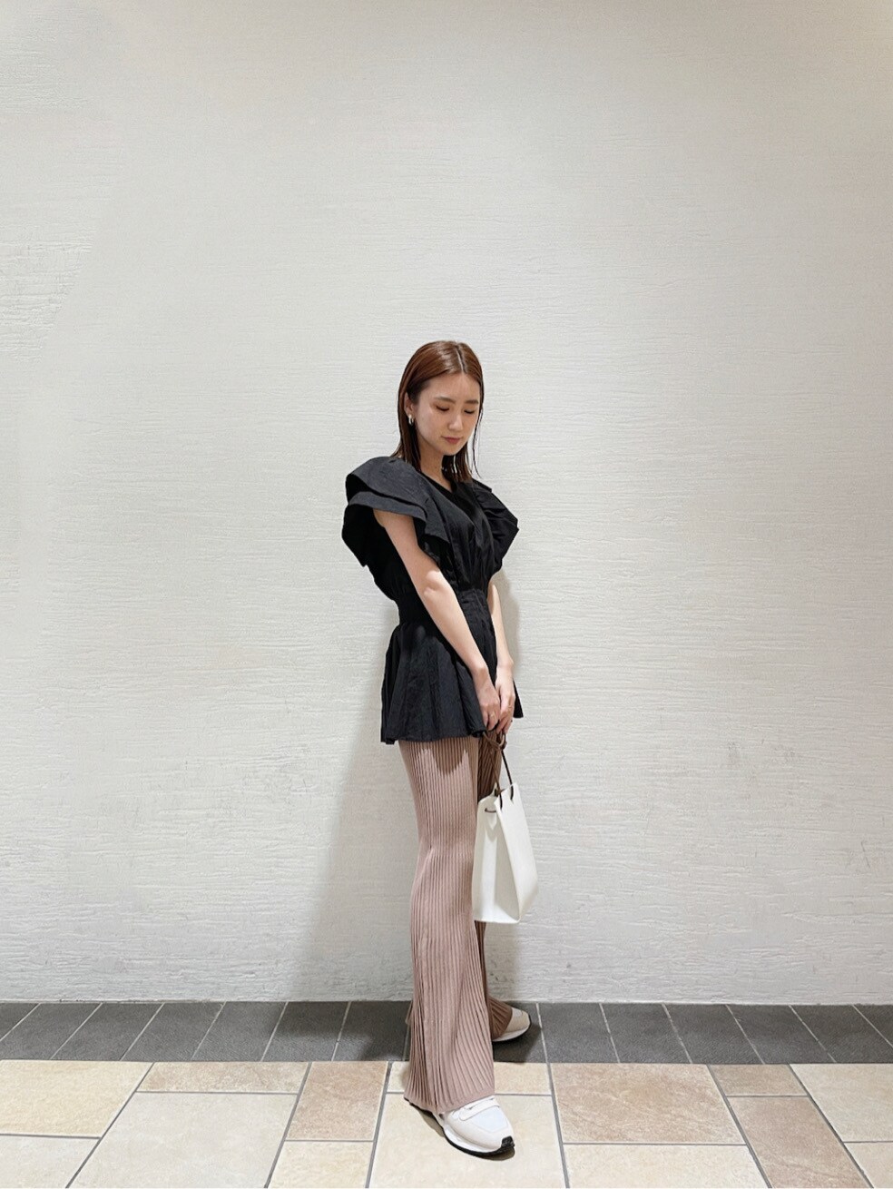 ホワイト系のハンドバッグ、ホワイト系のスニーカー、ブラック系のシャツ/ブラウスを着用したレディースの春コーディネートの4枚目の写真