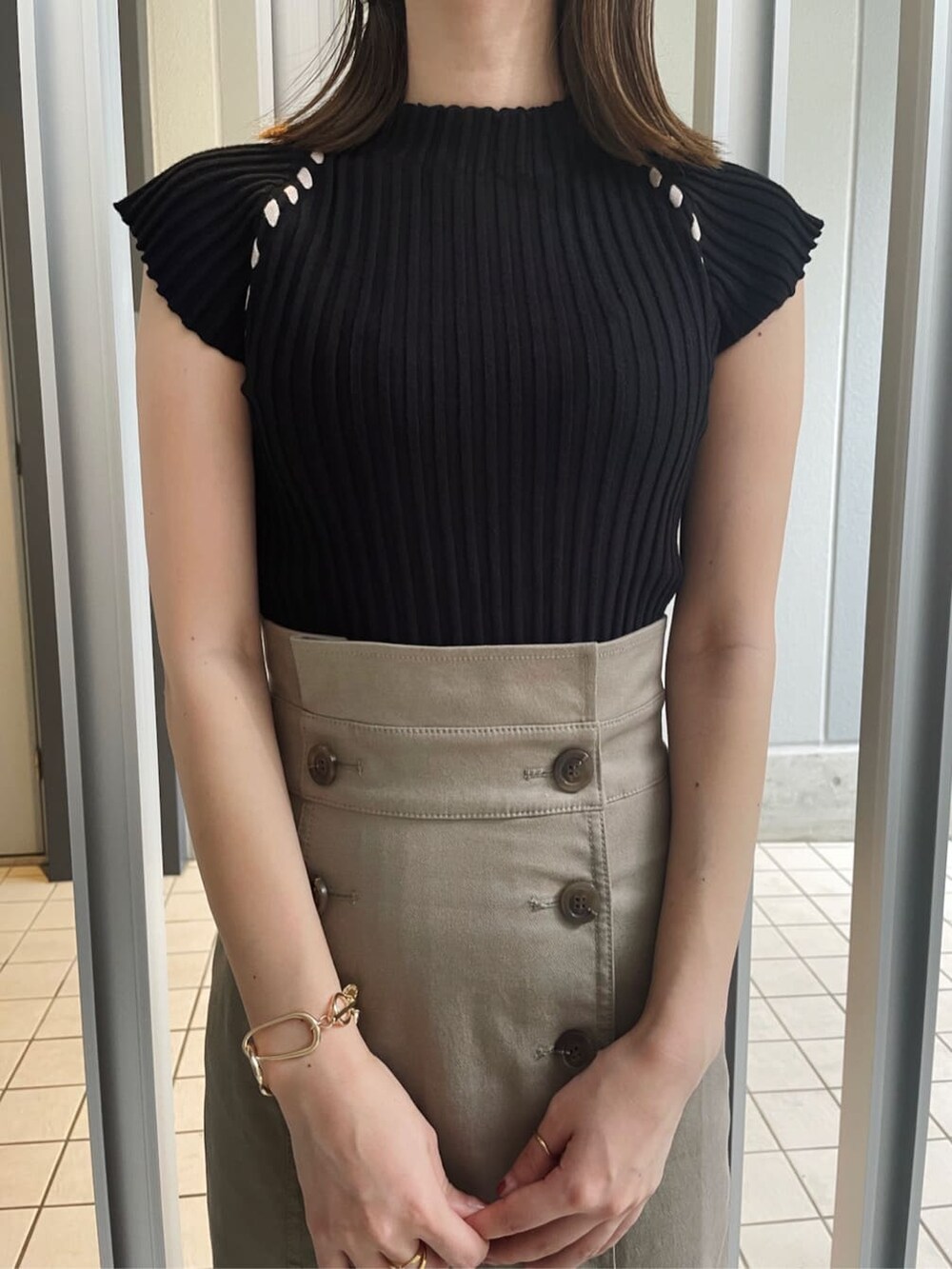 グレー系のスカート、ホワイト系のスニーカー、ブラック系のニット/セーターを着用したレディースの夏コーディネートの2枚目の写真