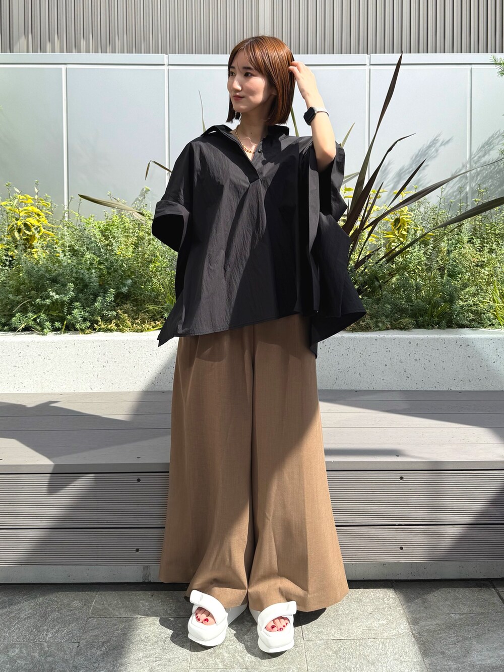 ブラック系のシャツ/ブラウス、ベージュ系のつなぎ/オールインワン、ホワイト系のサンダルを着用したレディースの春コーディネートの2枚目の写真