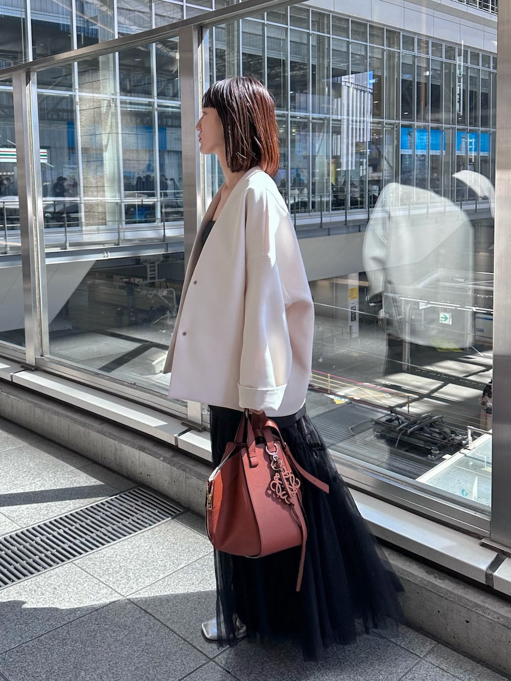 シルバー系のパンプス、ブラック系のスカート、ベージュ系のノーカラーコートを着用したレディースの春コーディネートの2枚目の写真