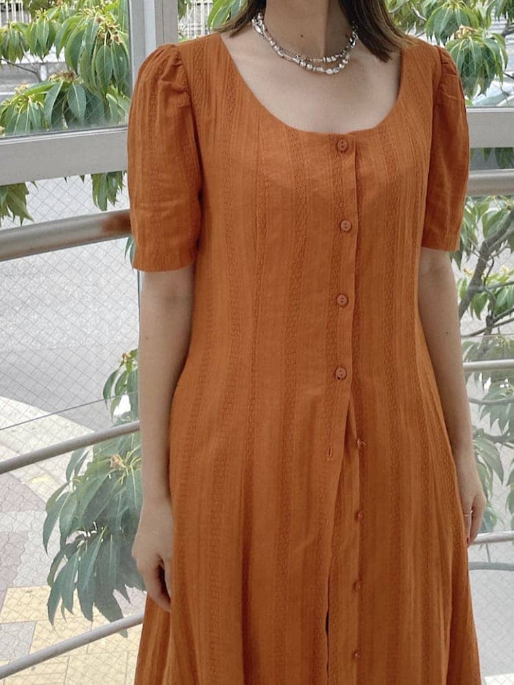 オレンジ系のワンピース、シルバー系のネックレスを着用したレディースの夏コーディネートの5枚目の写真