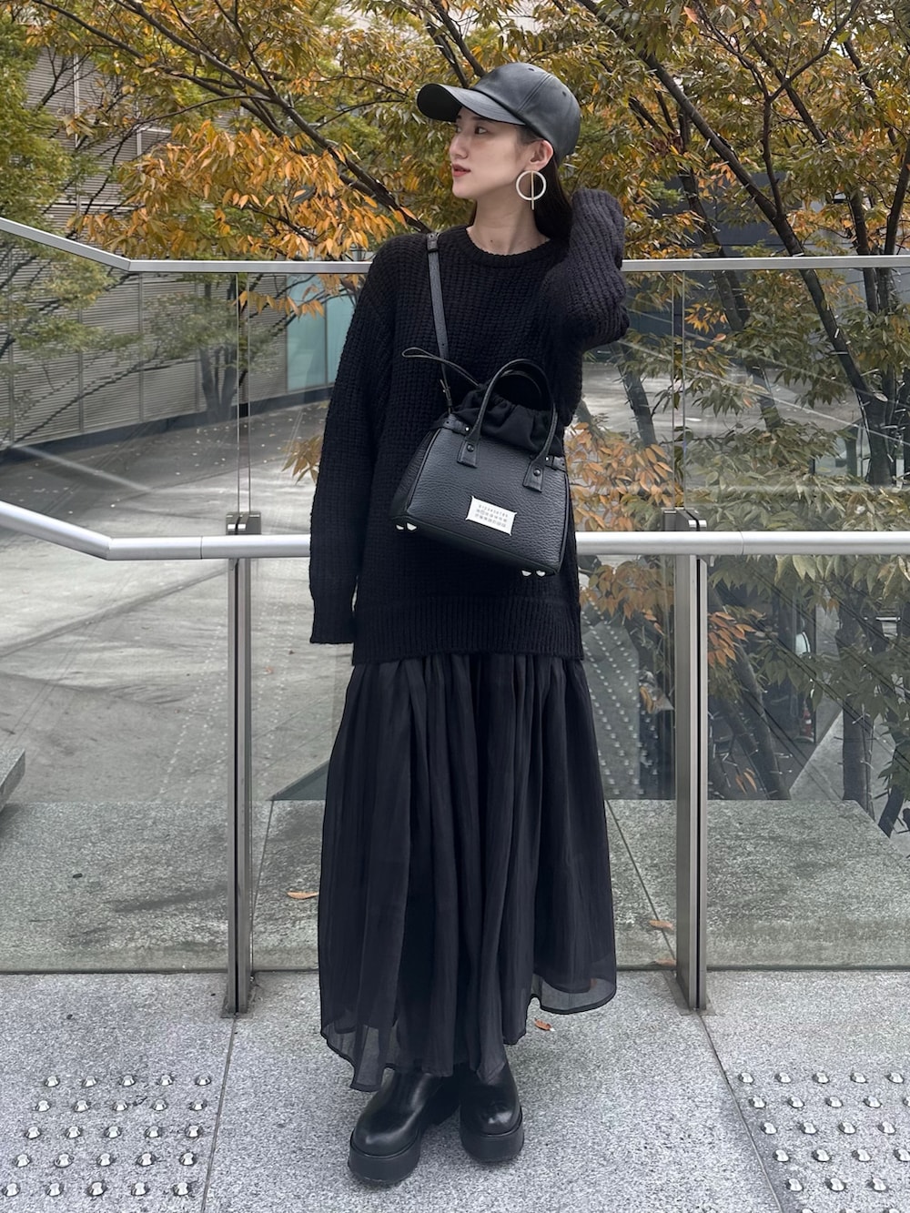 ブラック系のワンピース、ブラック系のショルダーバッグ、ブラック系のキャップを着用したレディースの秋コーディネートの2枚目の写真