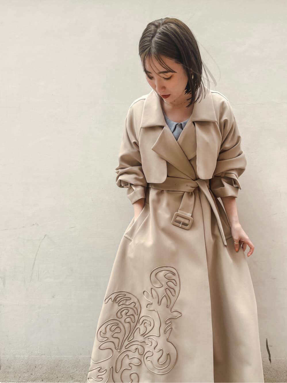 ベージュ系のトレンチコート、ブルー系のワンピース、ホワイト系のサンダルを着用したレディースの春コーディネートの4枚目の写真