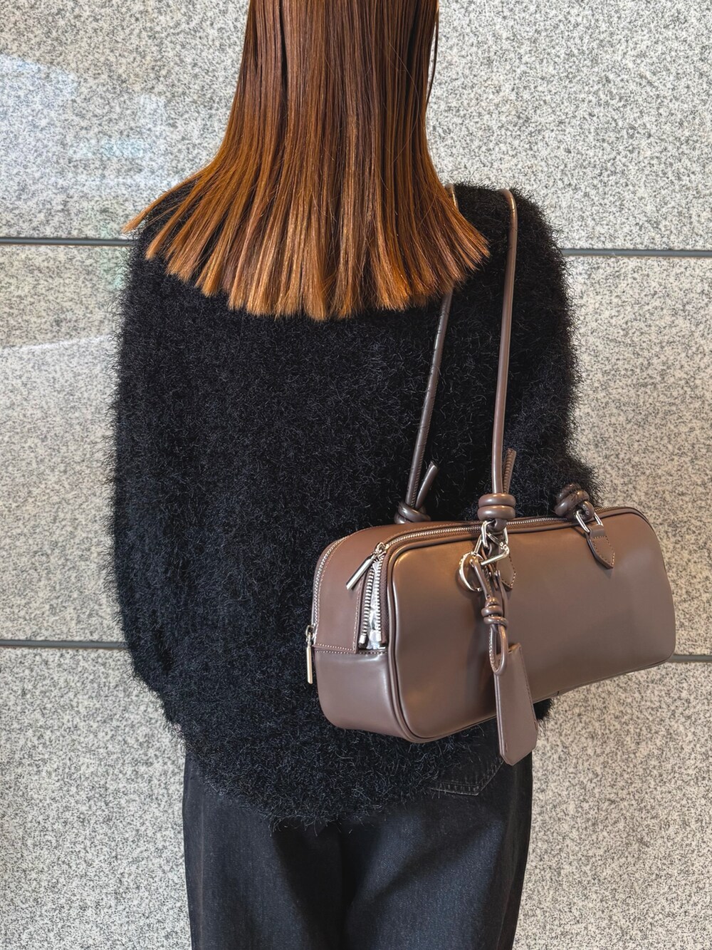 ブラック系のニット/セーター、ブラック系のデニムパンツ、ブラウン系のボストンバッグを着用したレディースの冬コーディネートの6枚目の写真