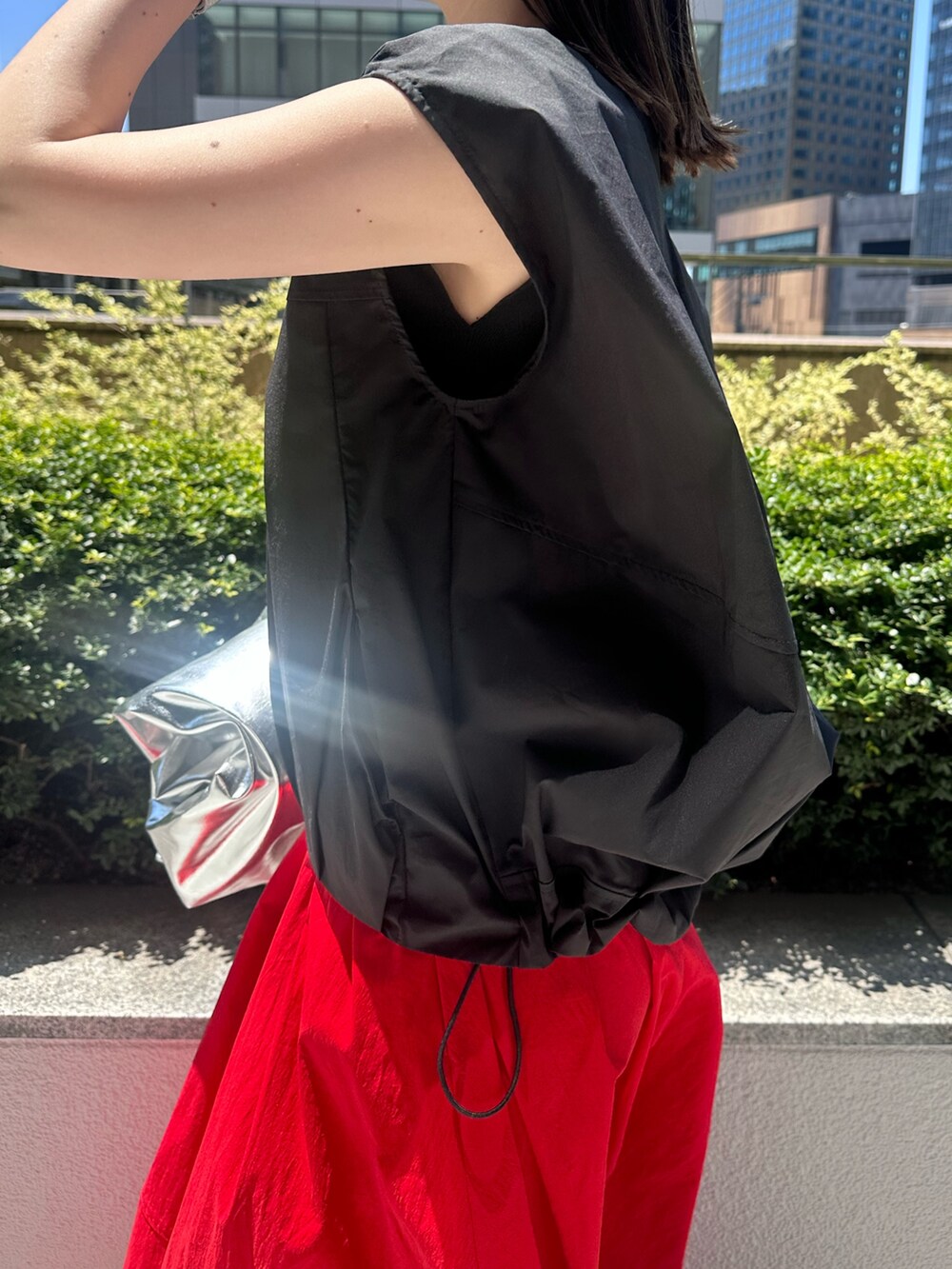 レッド系のスカート、シルバー系のパンプス、シルバー系のトートバッグを着用したレディースの夏コーディネートの6枚目の写真