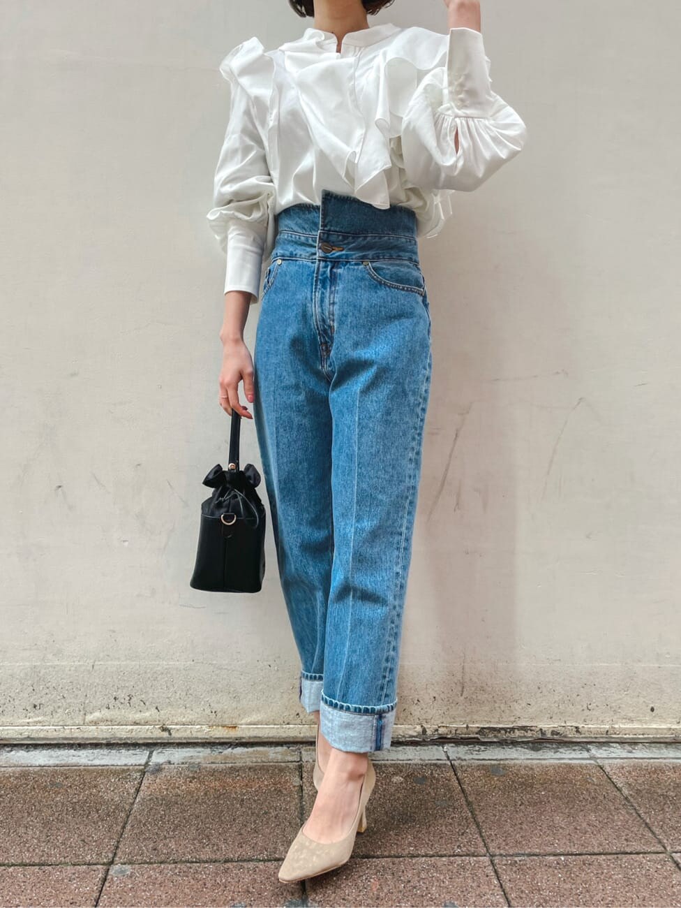 ベージュ系のパンプス、ブラック系のハンドバッグ、ブルー系のデニムパンツを着用したレディースの冬コーディネートの5枚目の写真