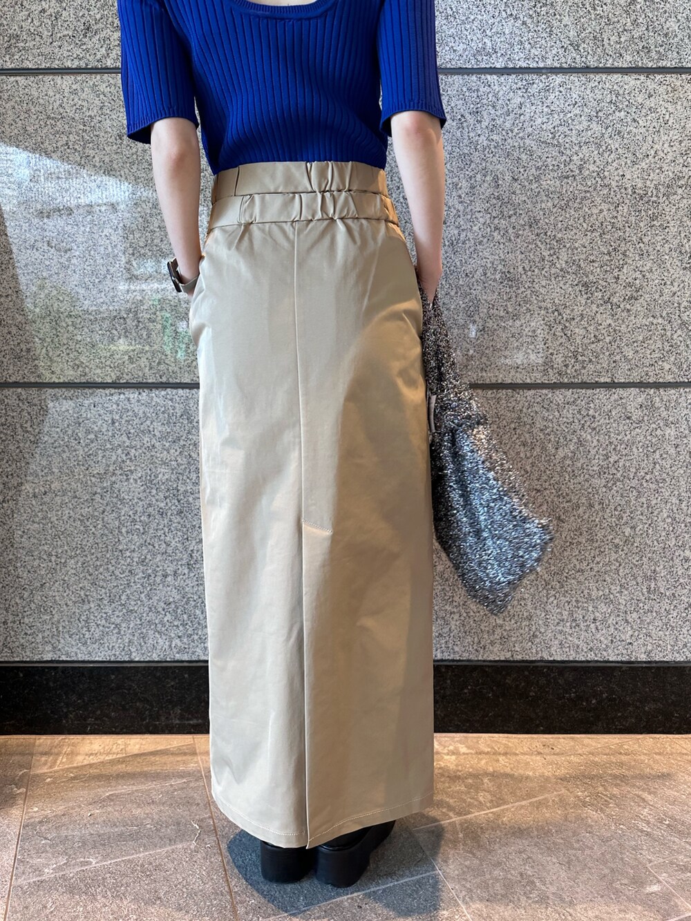 ブルー系のニット/セーター、ブラック系のノーカラージャケット、ベージュ系のスカートを着用したレディースの秋コーディネートの10枚目の写真