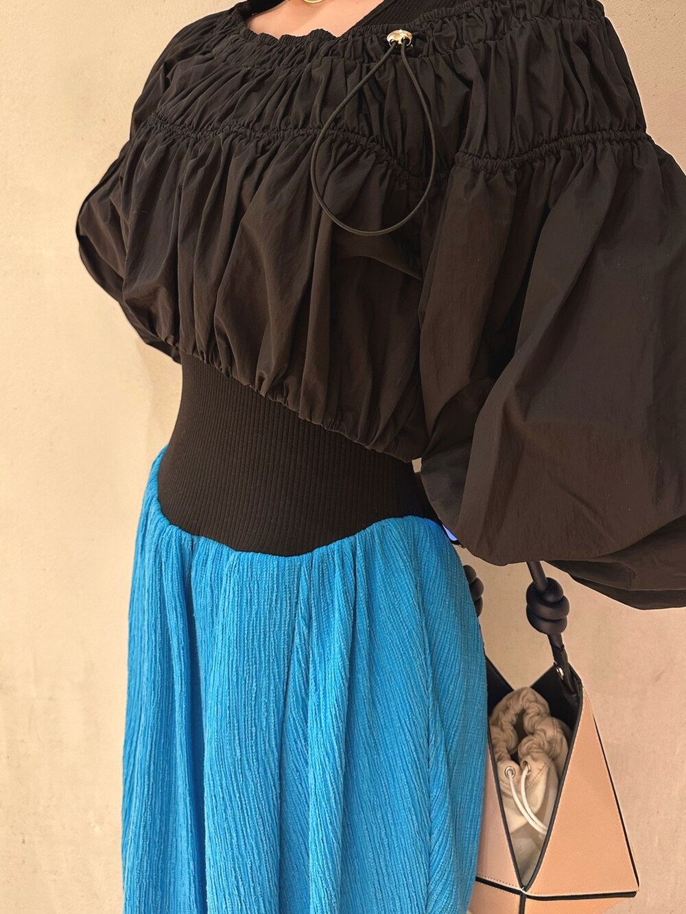 ベージュ系のハンドバッグ、ブルー系のワンピース、ホワイト系のスニーカーを着用したレディースの冬コーディネートの4枚目の写真