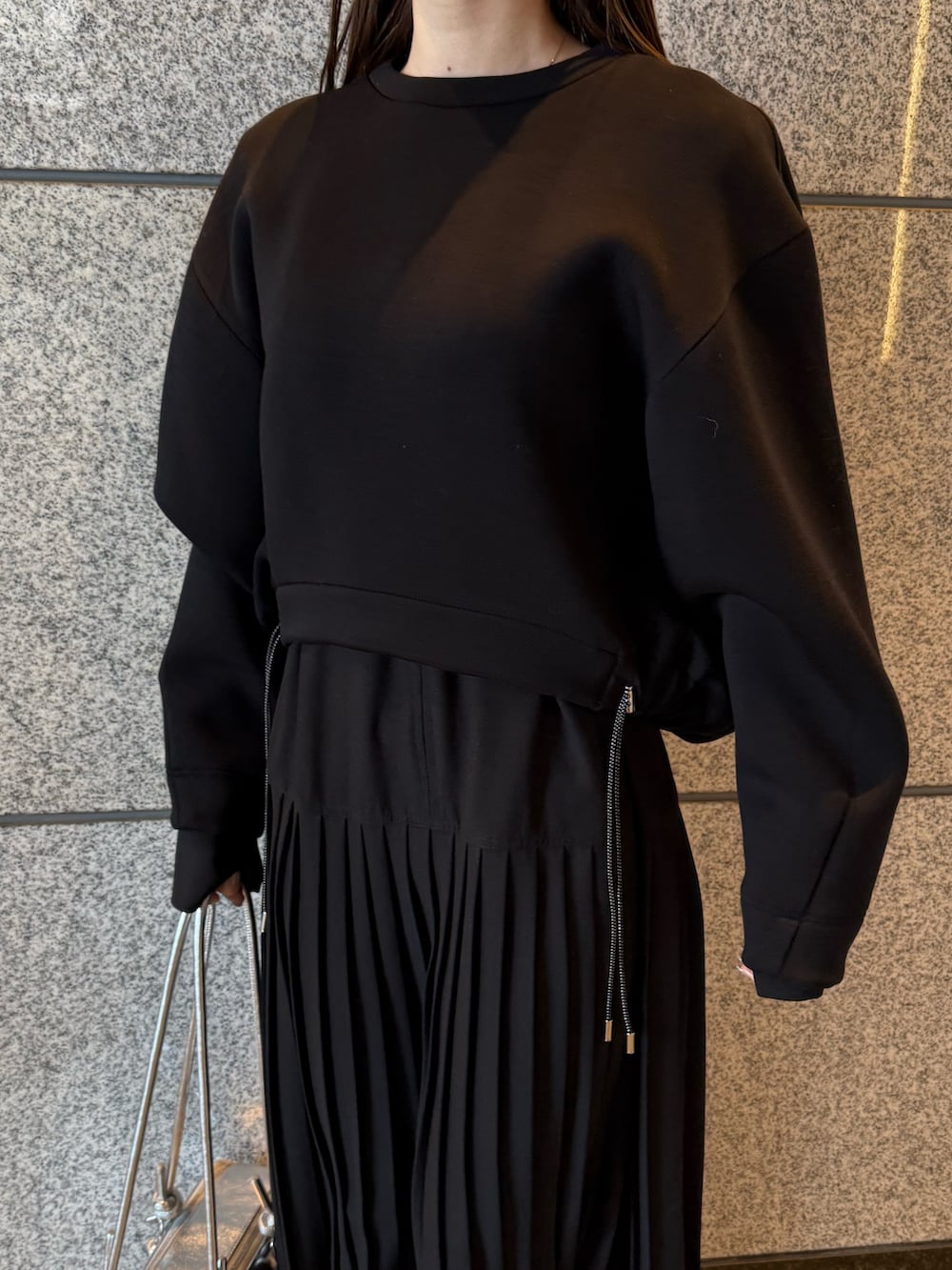 ブラック系のスウェット、シルバー系のボストンバッグ、ブラック系のワンピースを着用したレディースの冬コーディネートの7枚目の写真