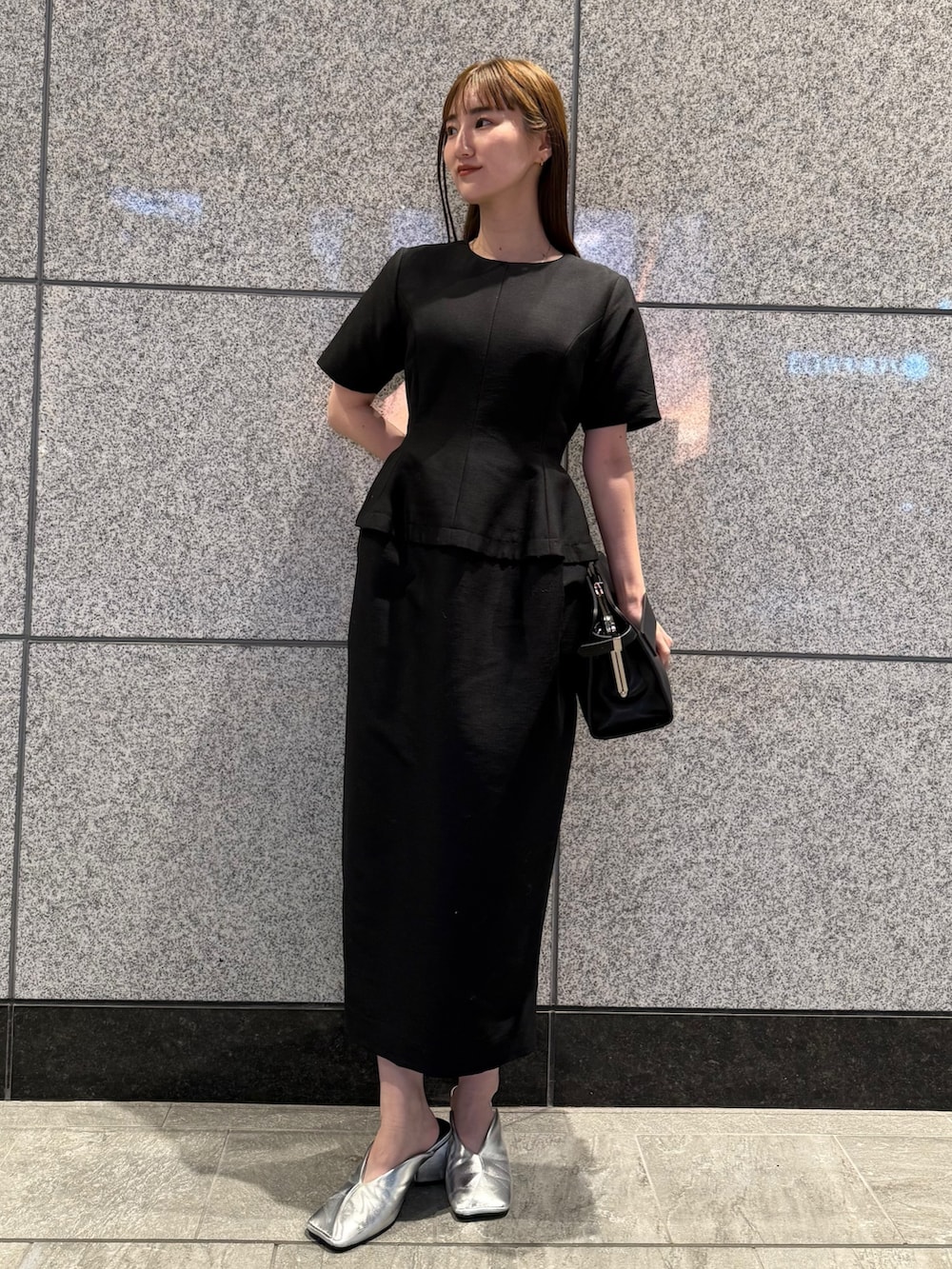 ブラック系のワンピース、ブラック系のハンドバッグを着用したレディースの冬コーディネートの2枚目の写真