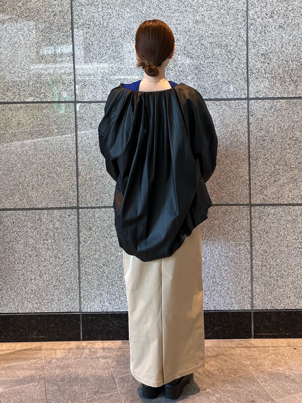 ブルー系のニット/セーター、ブラック系のノーカラージャケット、ベージュ系のスカートを着用したレディースの秋コーディネートの5枚目の写真