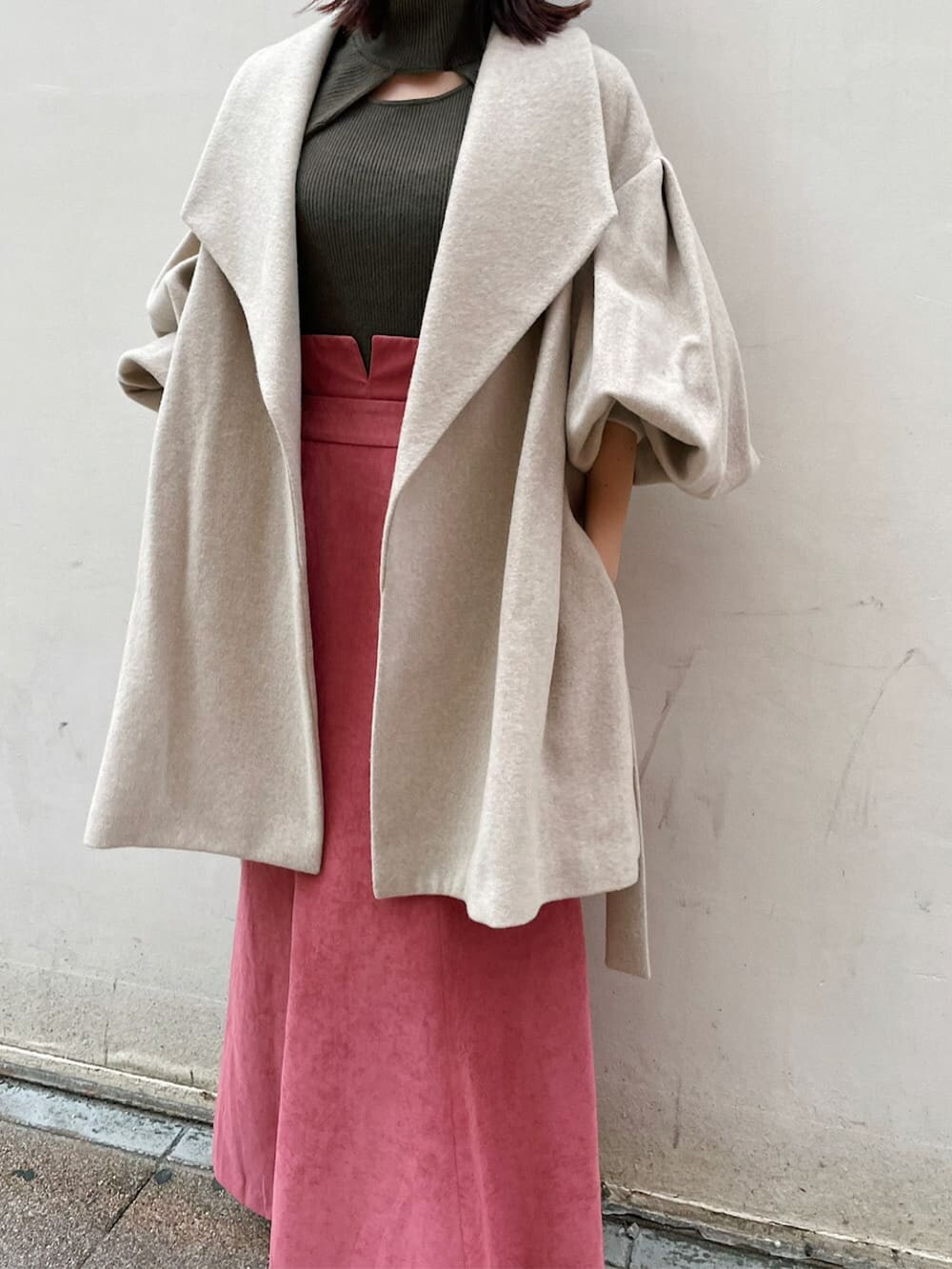 ブラック系のブーツ、ベージュ系のその他アウター、ピンク系のスカートを着用したレディースの秋コーディネートの3枚目の写真