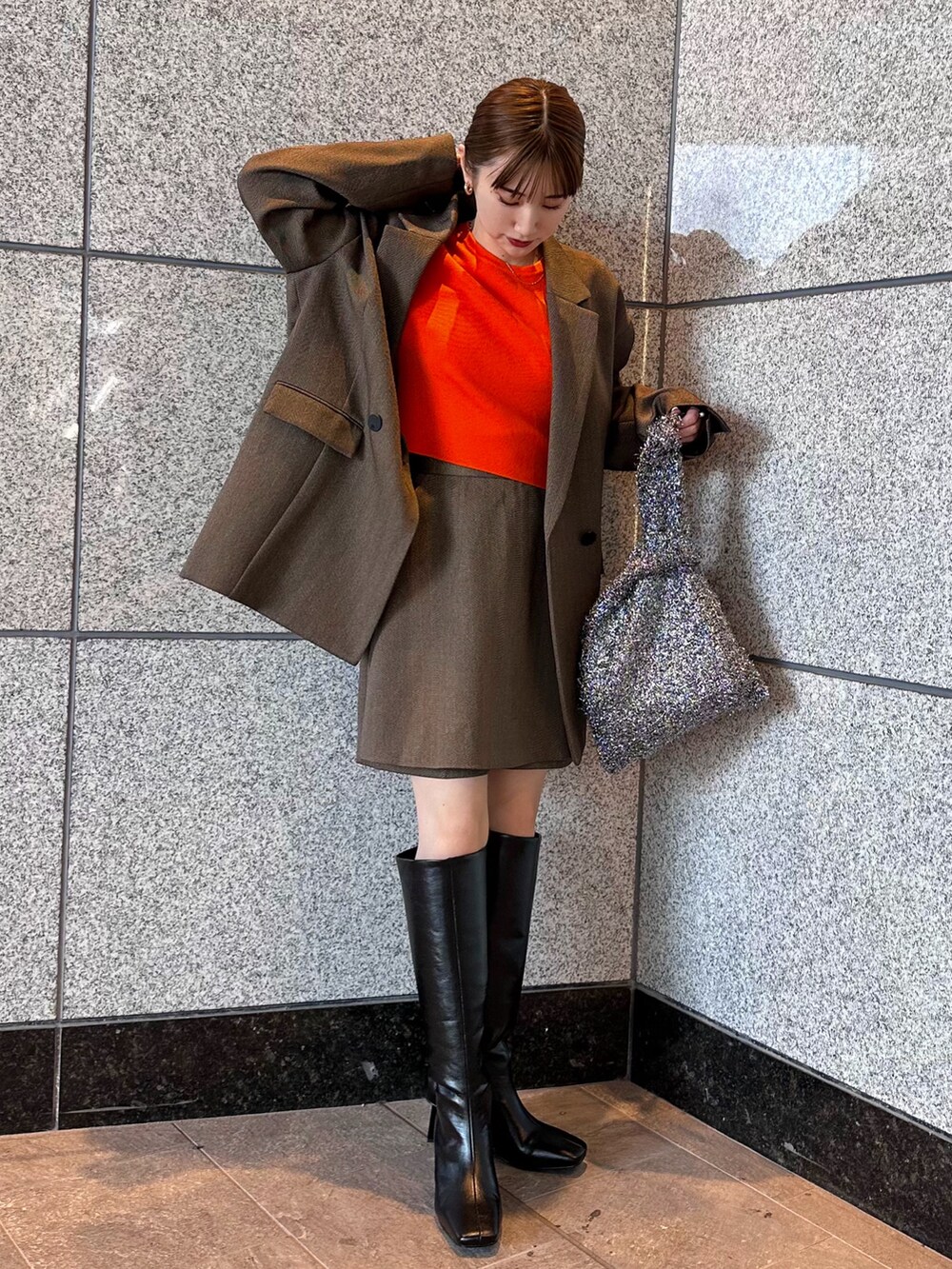 オレンジ系のニット/セーター、ブラウン系のテーラードジャケット、ブラウン系のスカートを着用したレディースの秋コーディネートの3枚目の写真