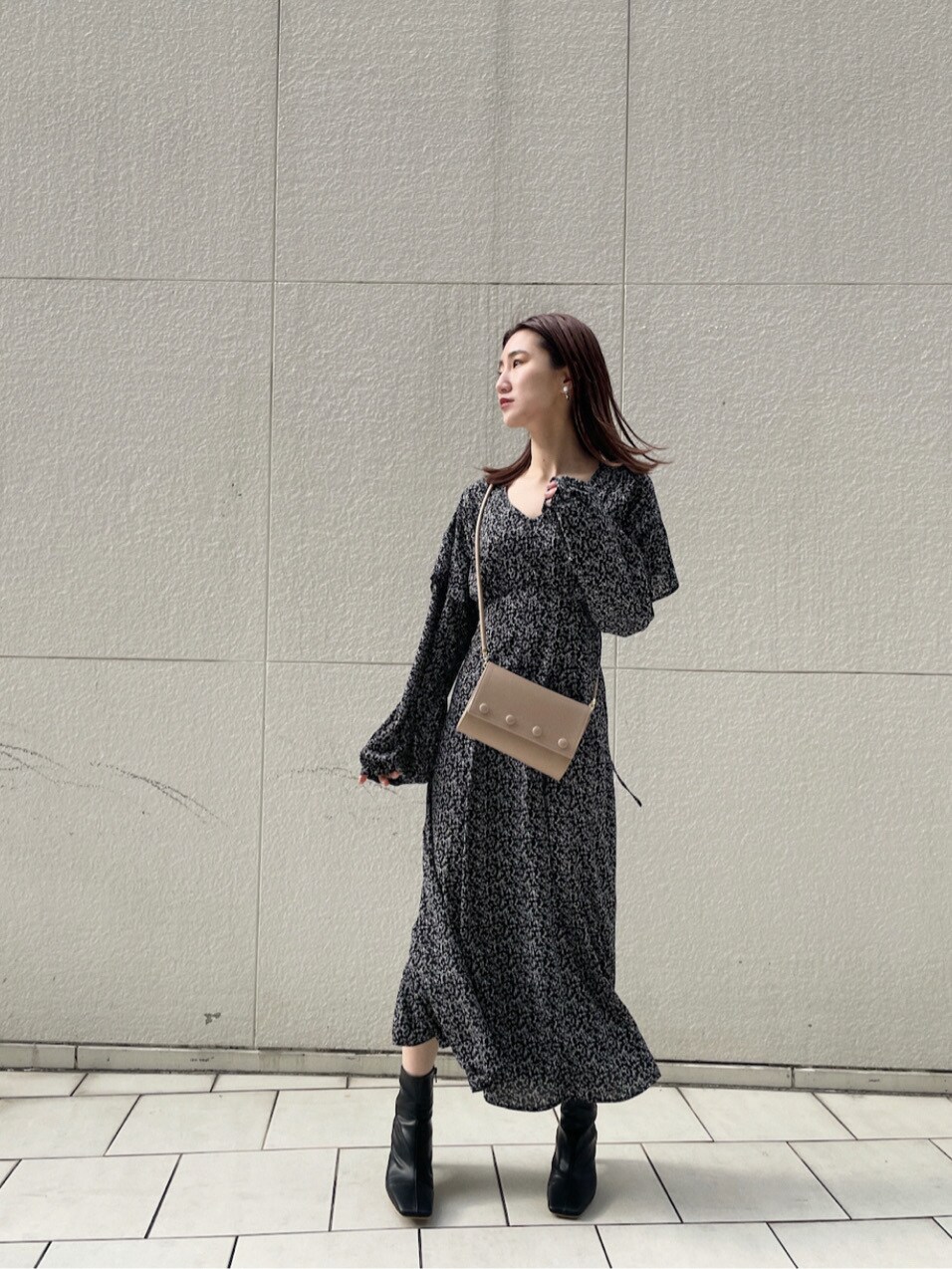 ベージュ系のハンドバッグ、ブラック系のワンピースを着用したレディースの冬コーディネートの2枚目の写真