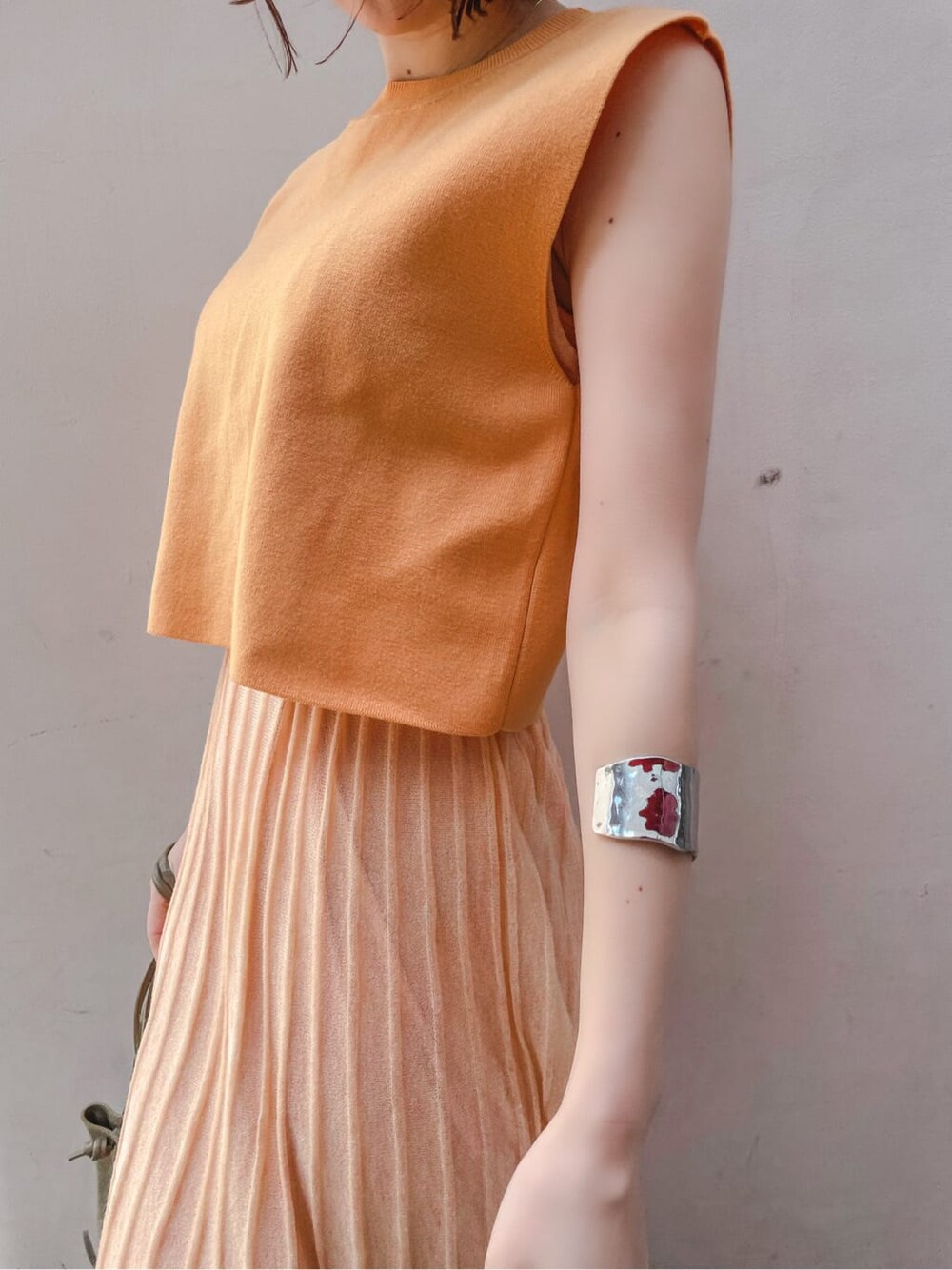 オレンジ系のワンピース、その他のパンプス、シルバー系のバングル/リストバンドを着用したレディースの春コーディネートの5枚目の写真