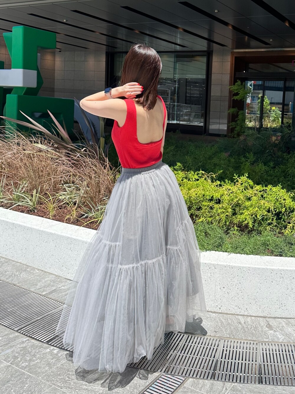 レッド系のタンクトップ、グレー系のスカートを着用したレディースの夏コーディネートの3枚目の写真