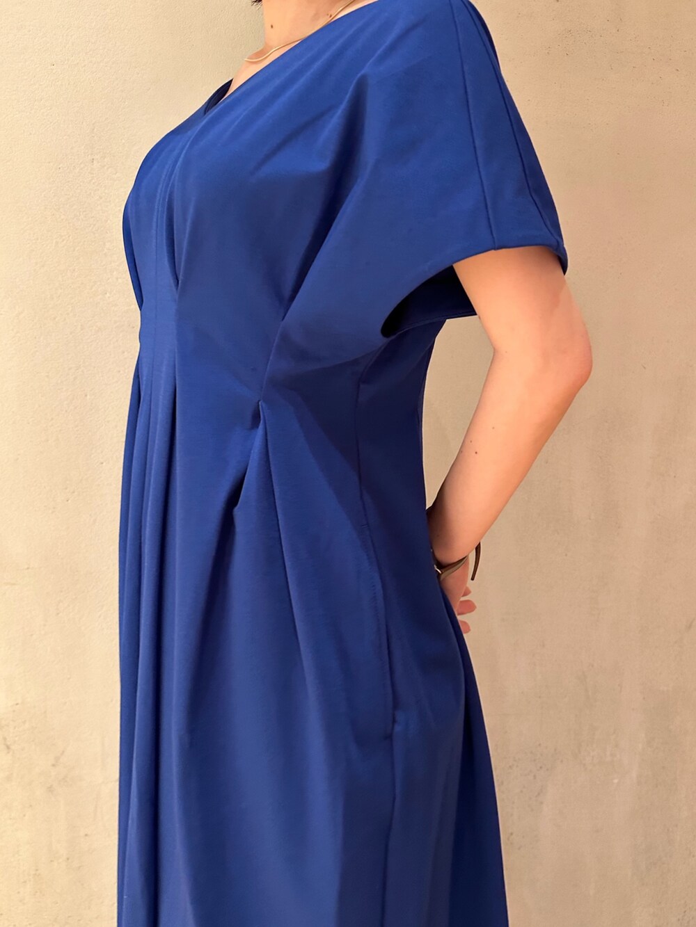 ブルー系のワンピース、ホワイト系のスニーカー、ブラック系のキャップを着用したレディースの春コーディネートの6枚目の写真