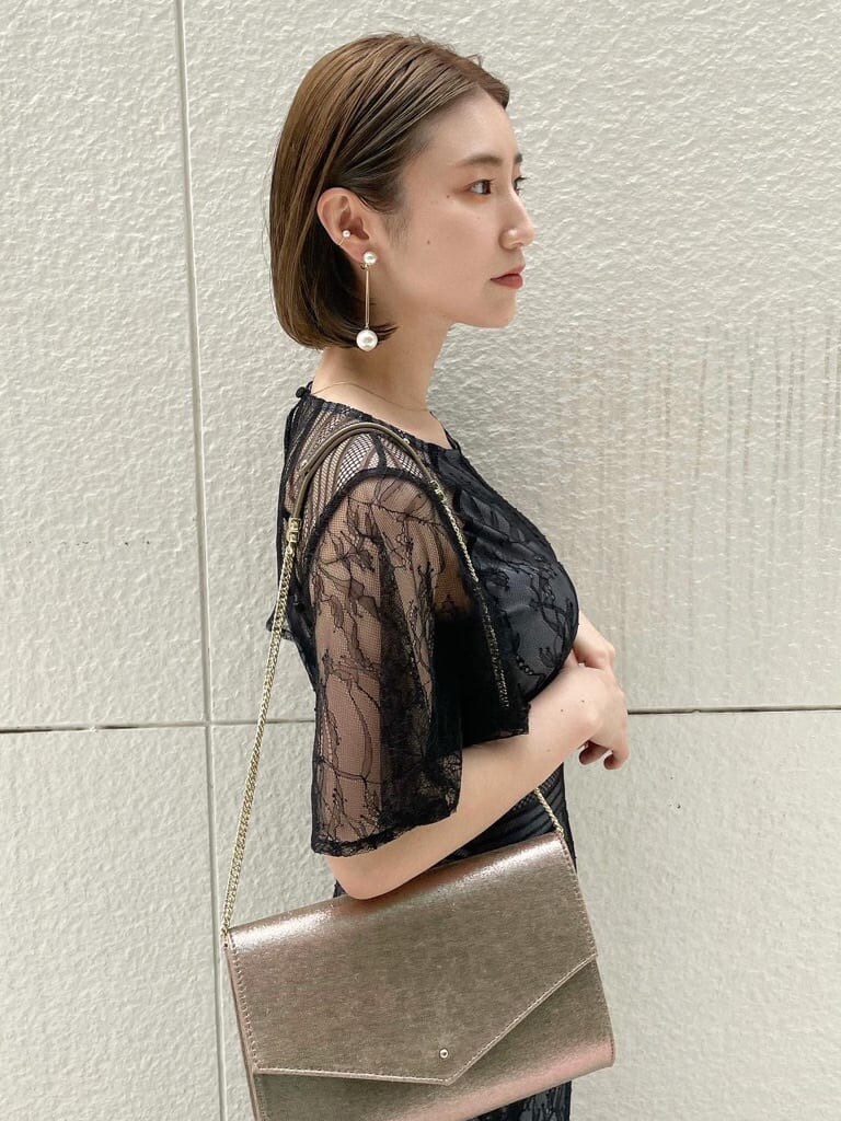 ゴールド系のパンプス、ゴールド系のクラッチバッグ、ブラック系のドレスを着用したレディースの春コーディネートの3枚目の写真