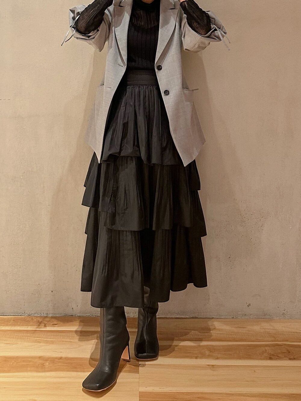 ブラック系のスカート、ブラック系のニット/セーター、グレー系のテーラードジャケットを着用したレディースの秋コーディネートの3枚目の写真