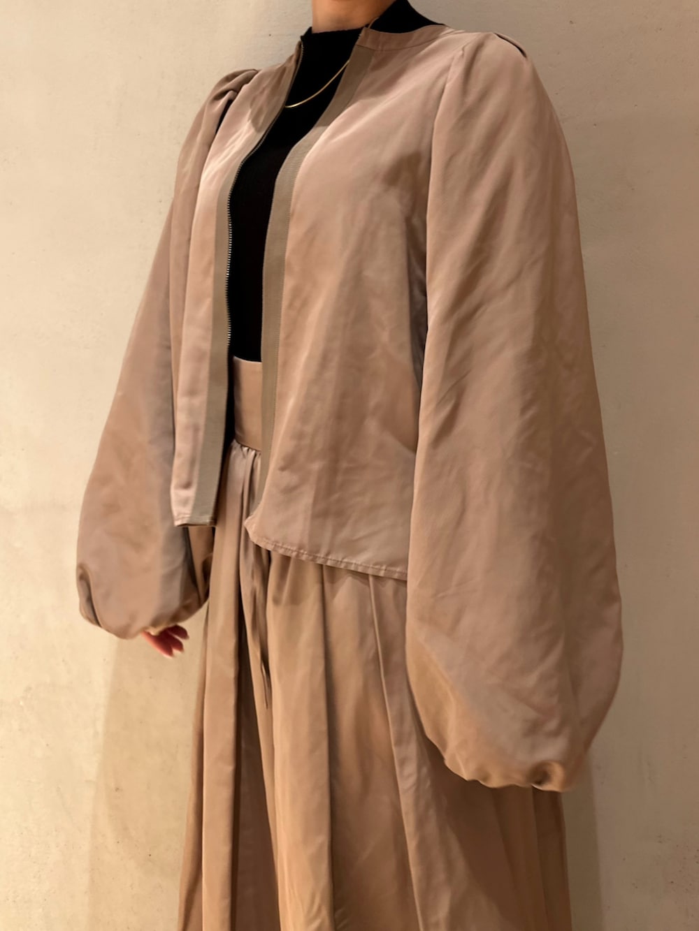 ブラック系のニット/セーター、ベージュ系のスカート、ブラック系のスニーカーを着用したレディースの冬コーディネートの7枚目の写真