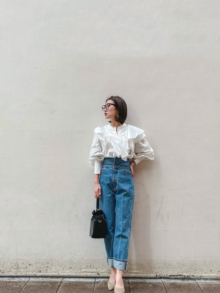 ベージュ系のパンプス、ブラック系のハンドバッグ、ブルー系のデニムパンツを着用したレディースの冬コーディネートの4枚目の写真