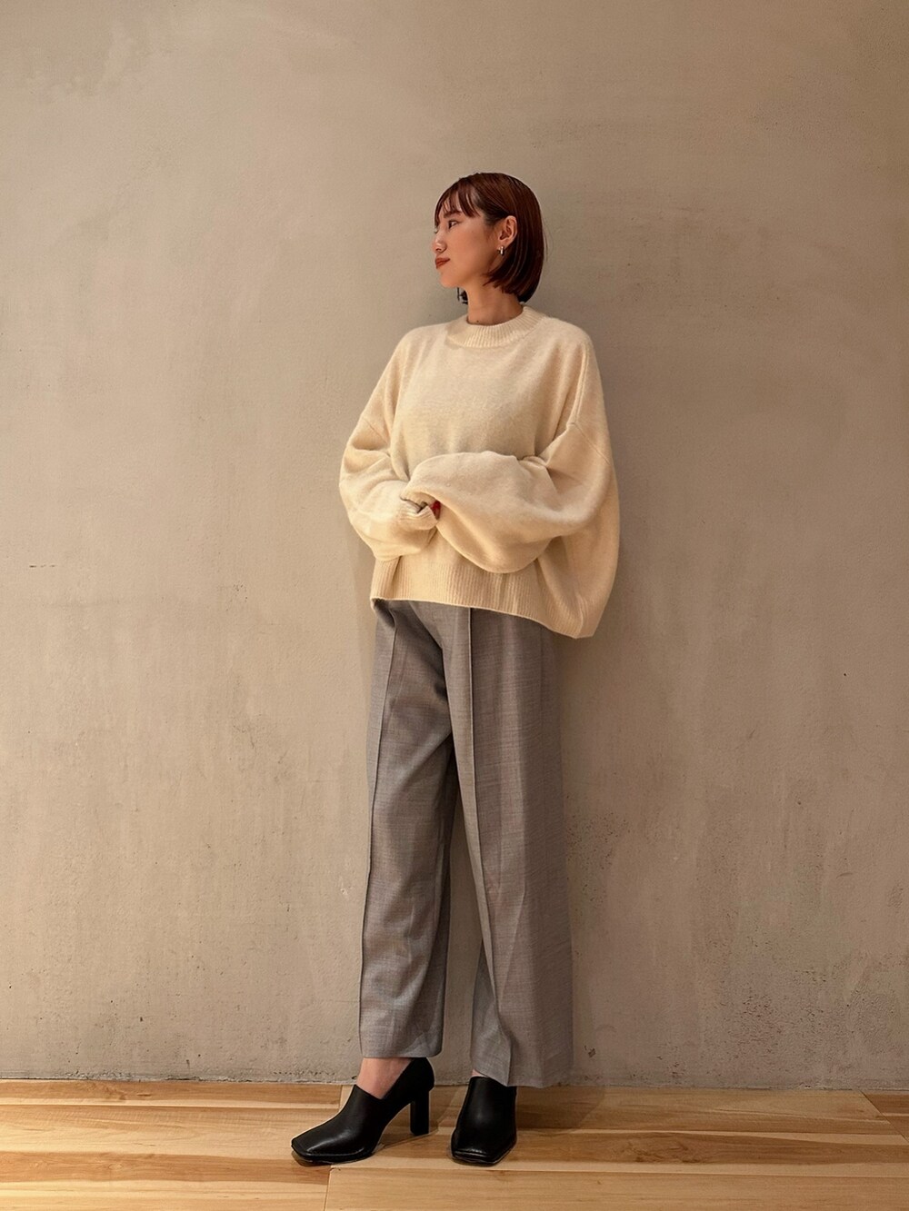ホワイト系のニット/セーター、グレー系のその他パンツ、ブラック系のブーティを着用したレディースの秋コーディネートの2枚目の写真