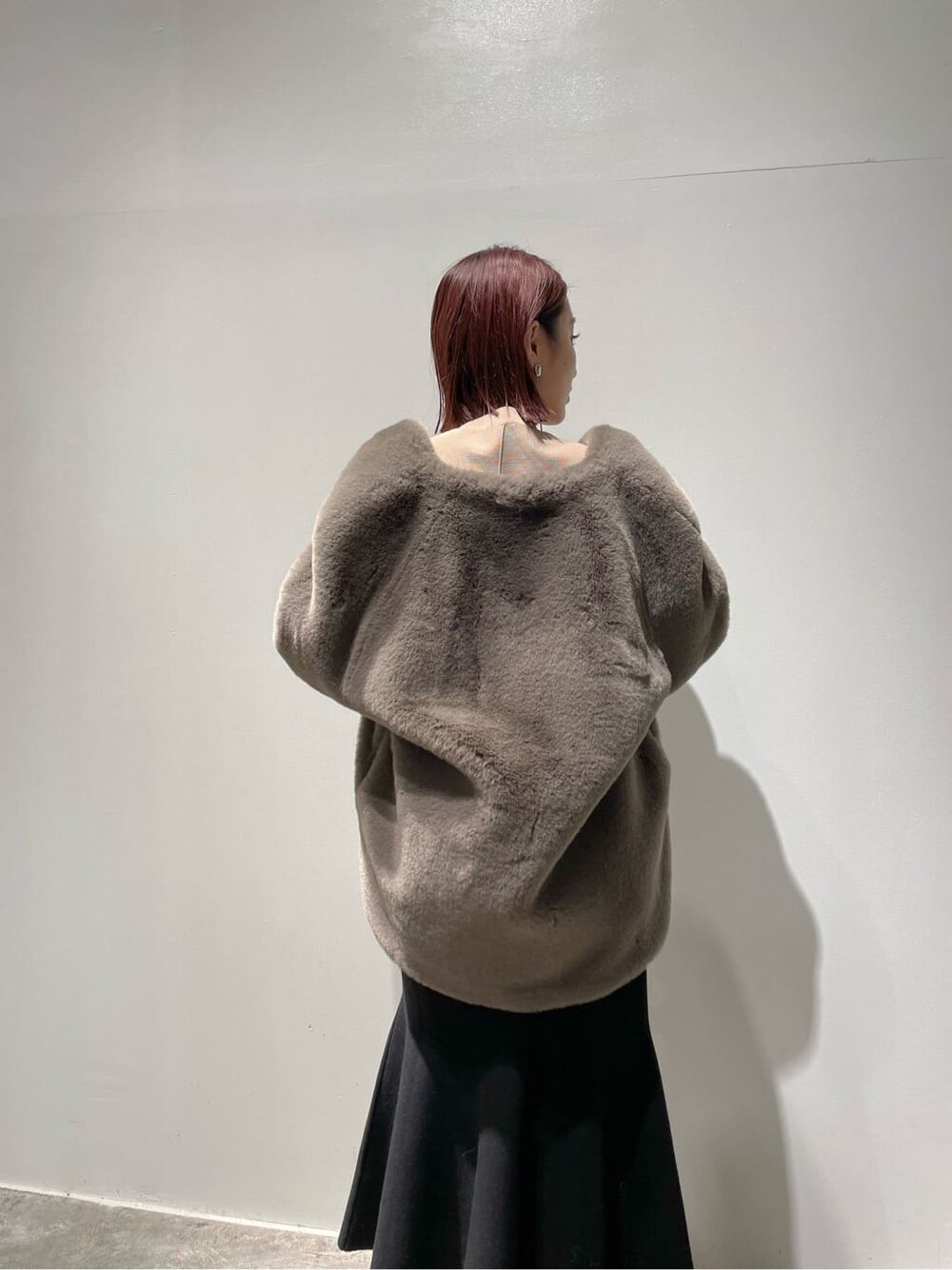 ブラウン系のノーカラーコート、ベージュ系のニット/セーター、ブラック系のブーツを着用したレディースの秋コーディネートの4枚目の写真