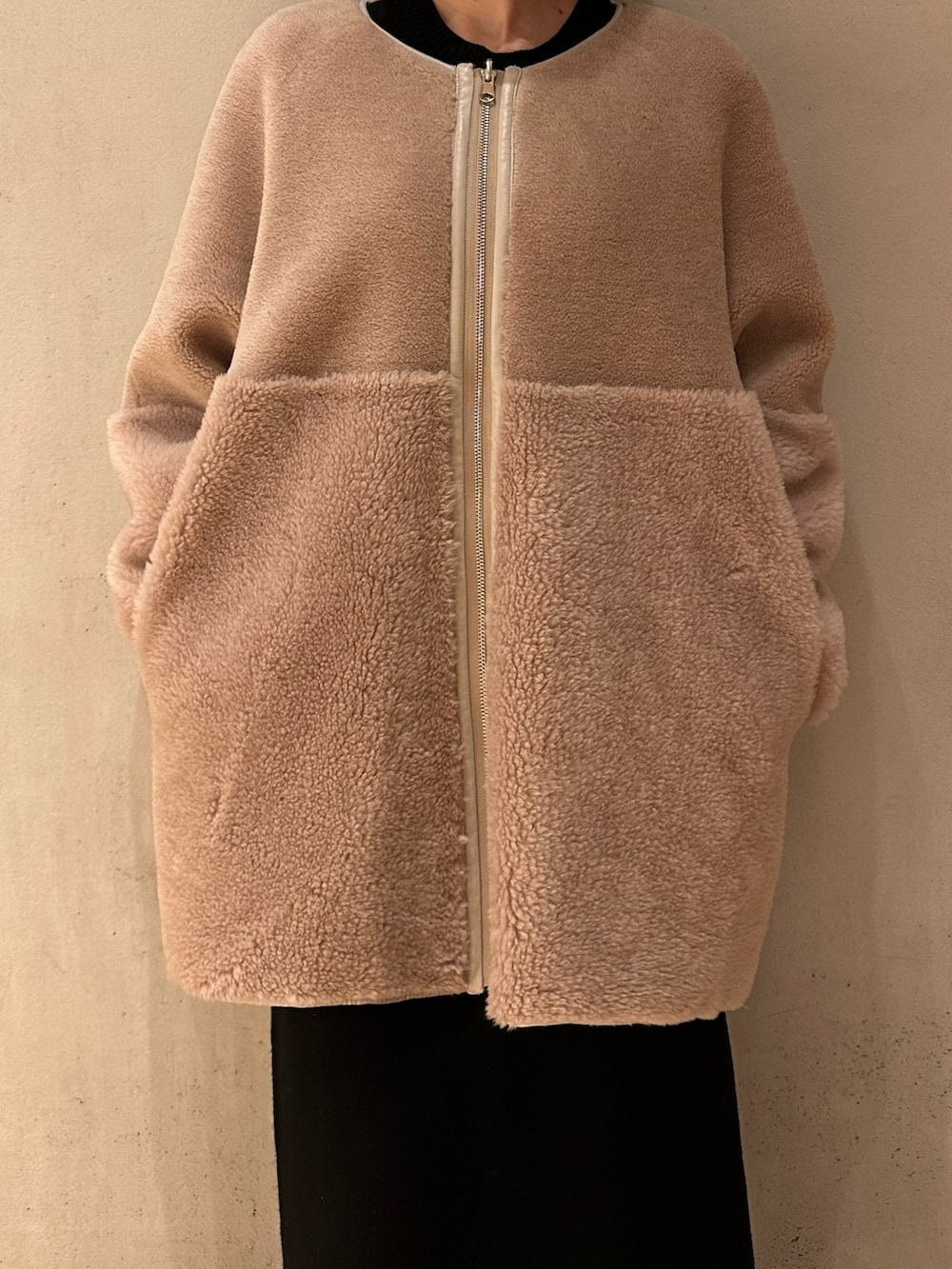 ブラック系のスカート、ブラック系のブーツ、ベージュ系のノーカラーコートを着用したレディースの夏コーディネートの4枚目の写真