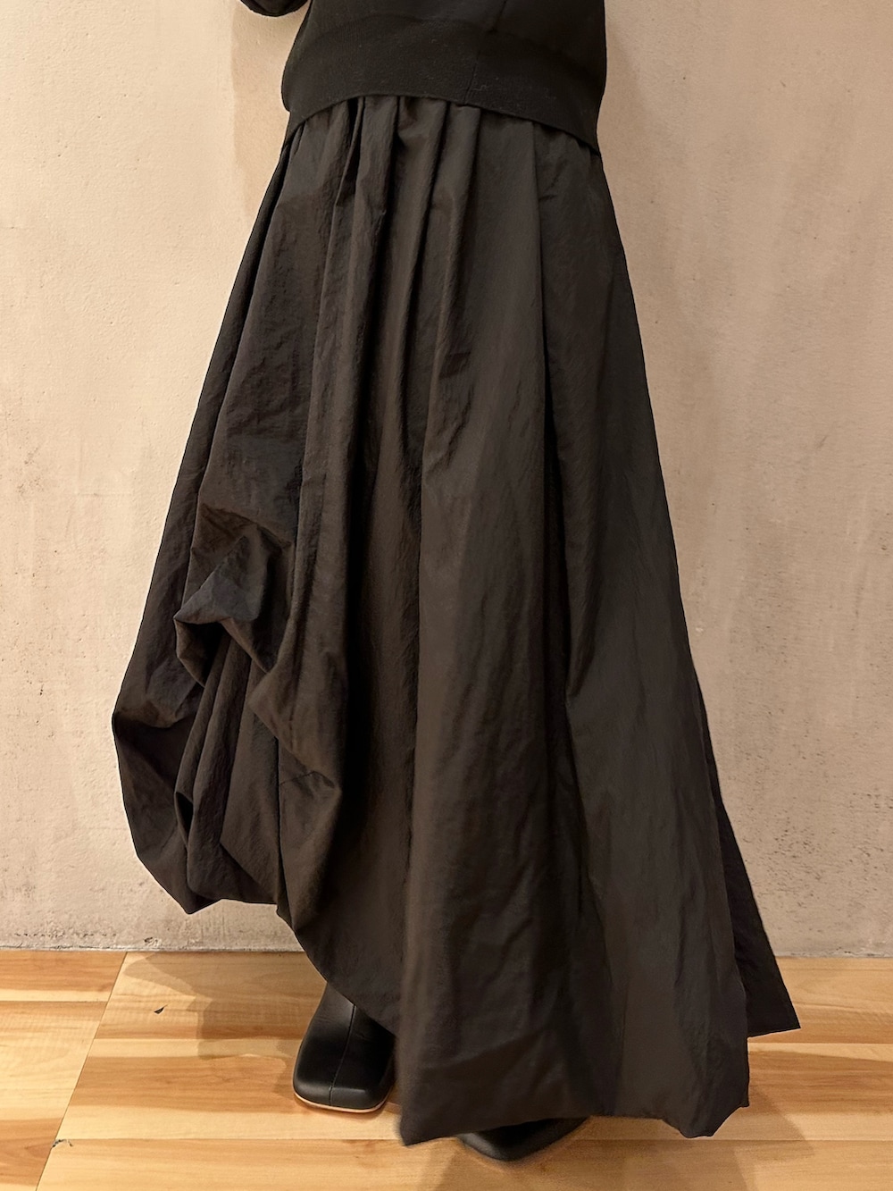 ブラック系のスカート、ブラック系のニット/セーター、ブラック系のブーツを着用したレディースの夏コーディネートの5枚目の写真