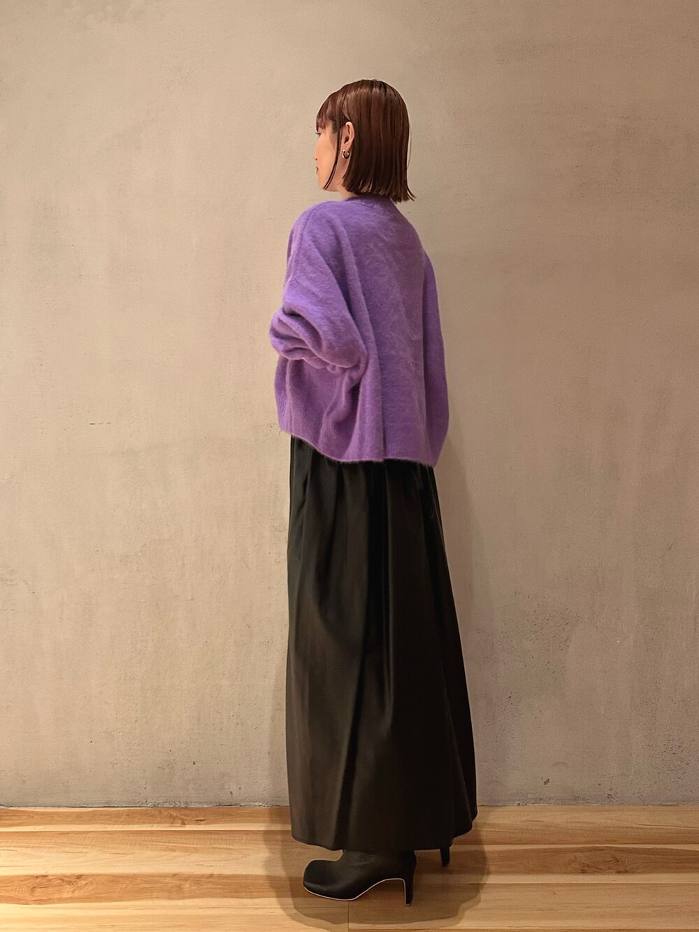 ブラック系のブーツ、ブラック系のジャンパースカート、パープル系のニット/セーターを着用したレディースの秋コーディネートの4枚目の写真