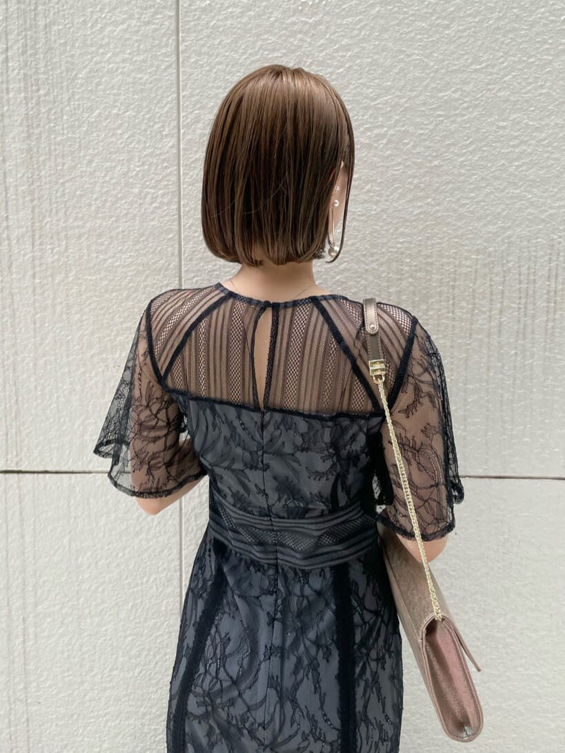 ゴールド系のパンプス、ゴールド系のクラッチバッグ、ブラック系のドレスを着用したレディースの春コーディネートの5枚目の写真