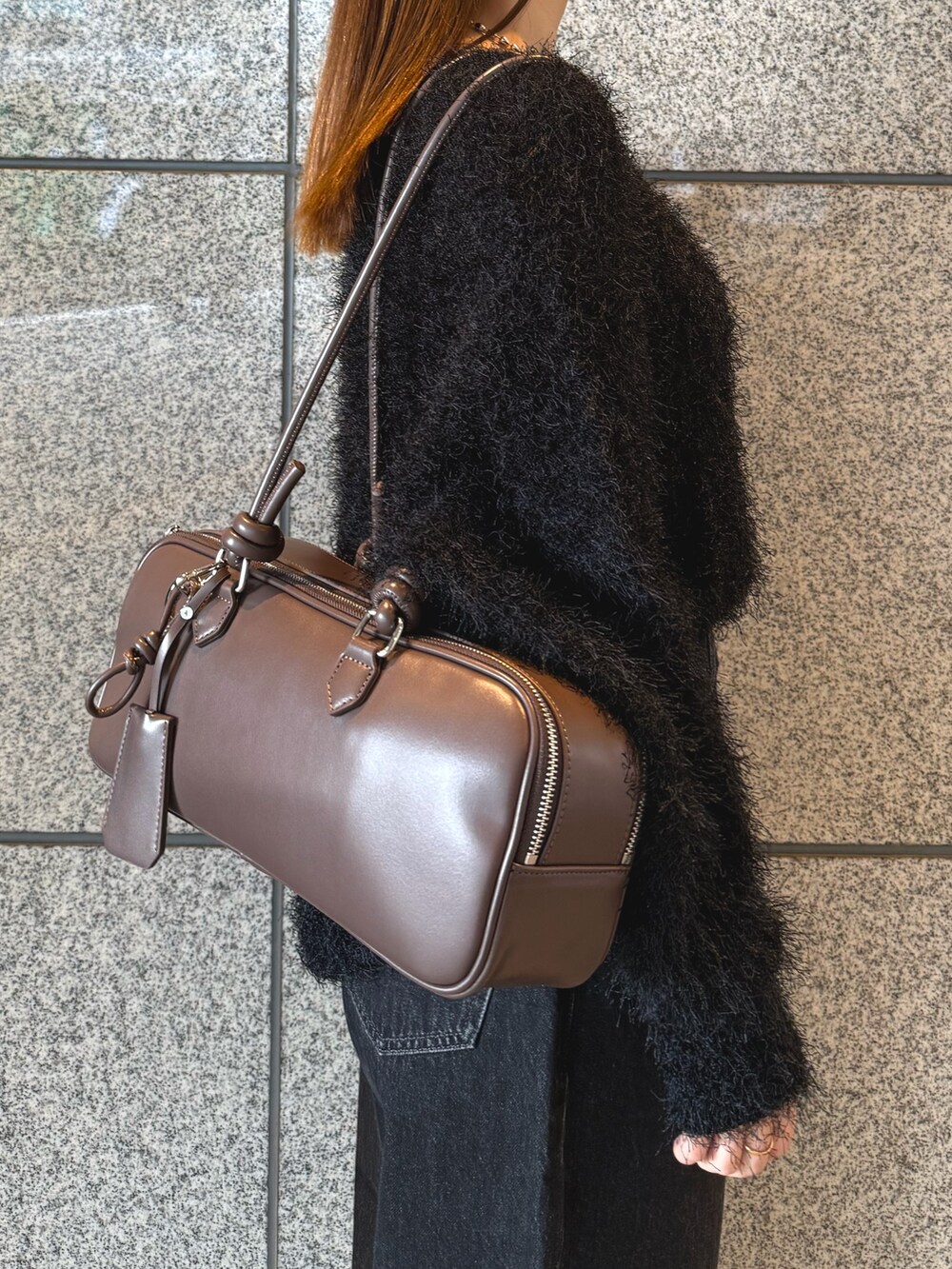 ブラック系のニット/セーター、ブラック系のデニムパンツ、ブラウン系のボストンバッグを着用したレディースの冬コーディネートの7枚目の写真