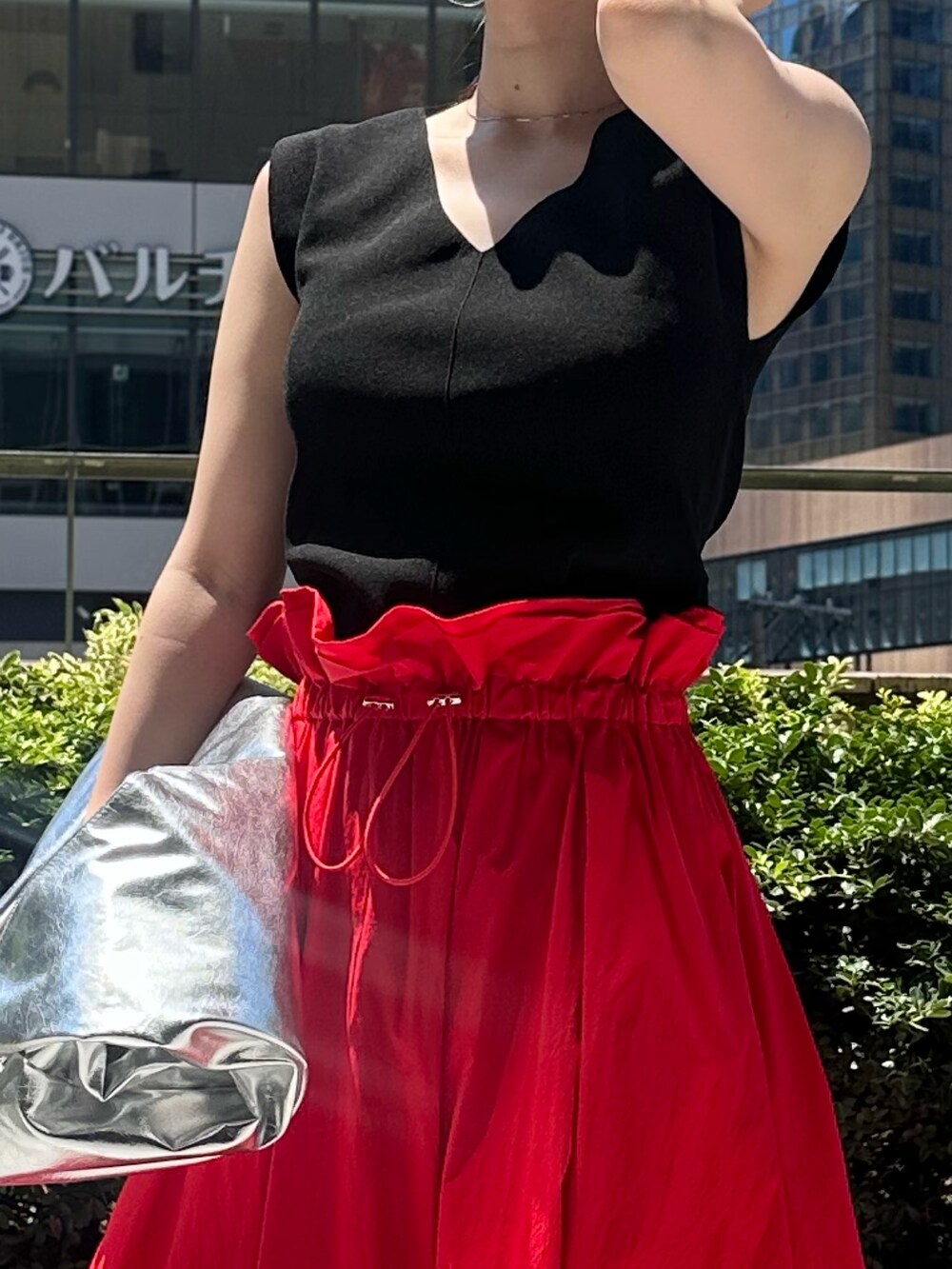 レッド系のスカート、シルバー系のトートバッグ、シルバー系のパンプスを着用したレディースの夏コーディネートの9枚目の写真