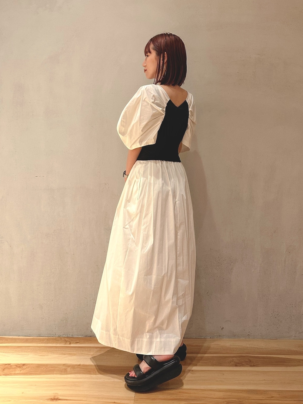 ブラック系のサンダル、ホワイト系のワンピース、ゴールド系のピアス（両耳用）を着用したレディースの夏コーディネートの2枚目の写真