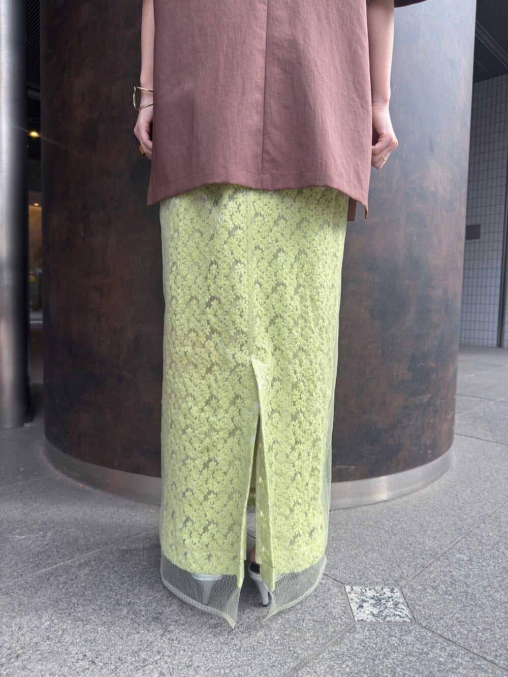 シルバー系のパンプス、ブラウン系のテーラードジャケット、グリーン系のスカートを着用したレディースの春コーディネートの9枚目の写真