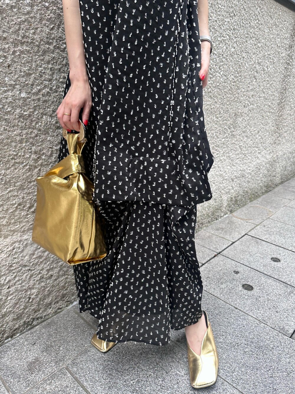 ブラック系のワンピース、ゴールド系のハンドバッグ、ゴールド系のパンプスを着用したレディースの夏コーディネートの7枚目の写真