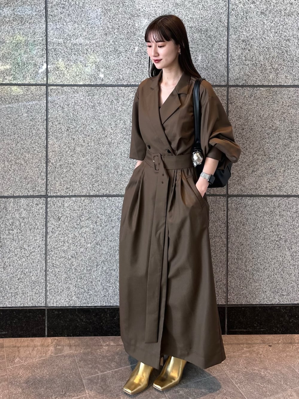 ブラウン系のワンピース、ゴールド系のブーツ、ブラック系のハンドバッグを着用したレディースの秋コーディネートの3枚目の写真