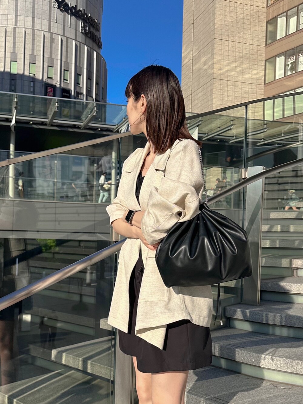 ブラック系のキャミソール、ベージュ系のテーラードジャケット、ブラック系のショルダーバッグを着用したレディースの春コーディネートの4枚目の写真