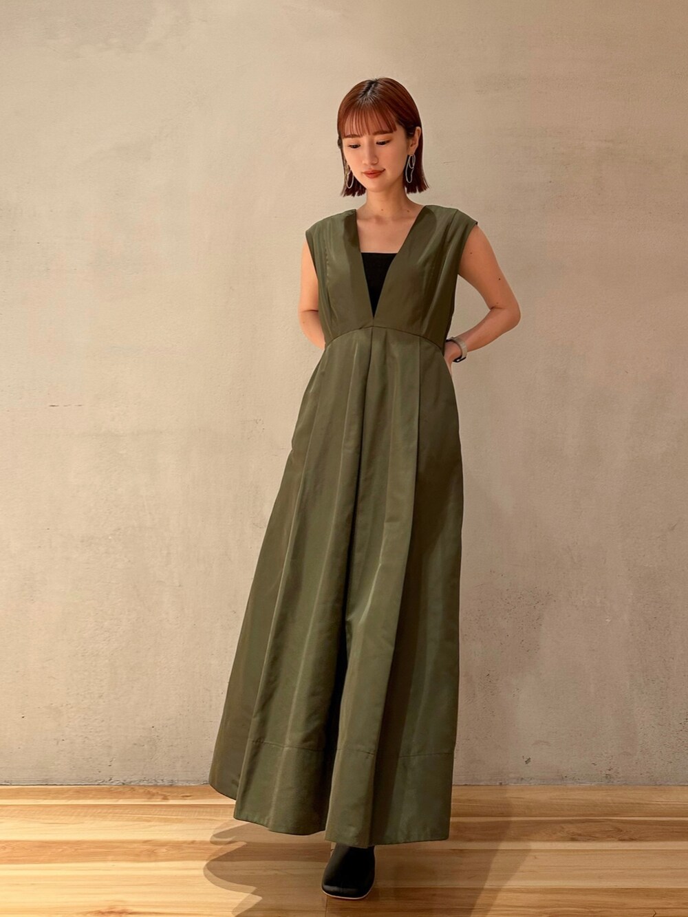 グリーン系のジャンパースカート、ブラック系のブーツを着用したレディースの夏コーディネートの2枚目の写真