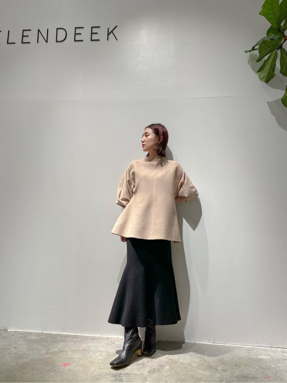 ブラウン系のノーカラーコート、ベージュ系のニット/セーター、ブラック系のブーツを着用したレディースの秋コーディネートの6枚目の写真