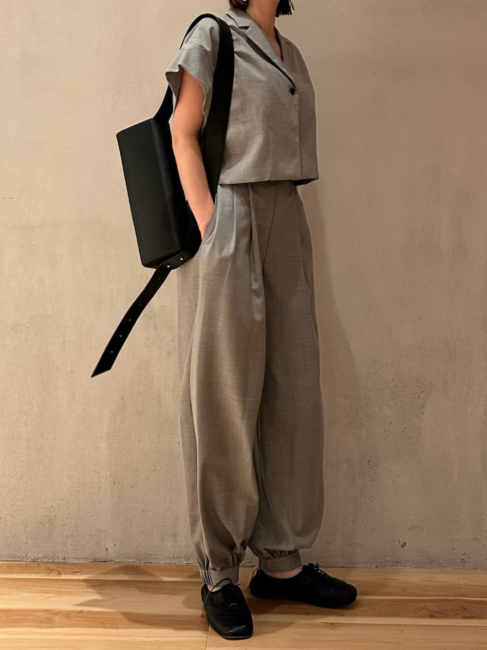 グレー系のテーラードジャケット、ブラック系のショルダーバッグ、ブラック系のバレエシューズを着用したレディースの夏コーディネートの3枚目の写真