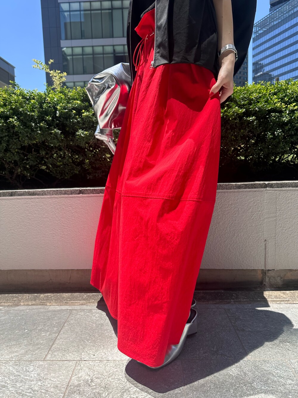 レッド系のスカート、シルバー系のトートバッグ、シルバー系のパンプスを着用したレディースの夏コーディネートの7枚目の写真