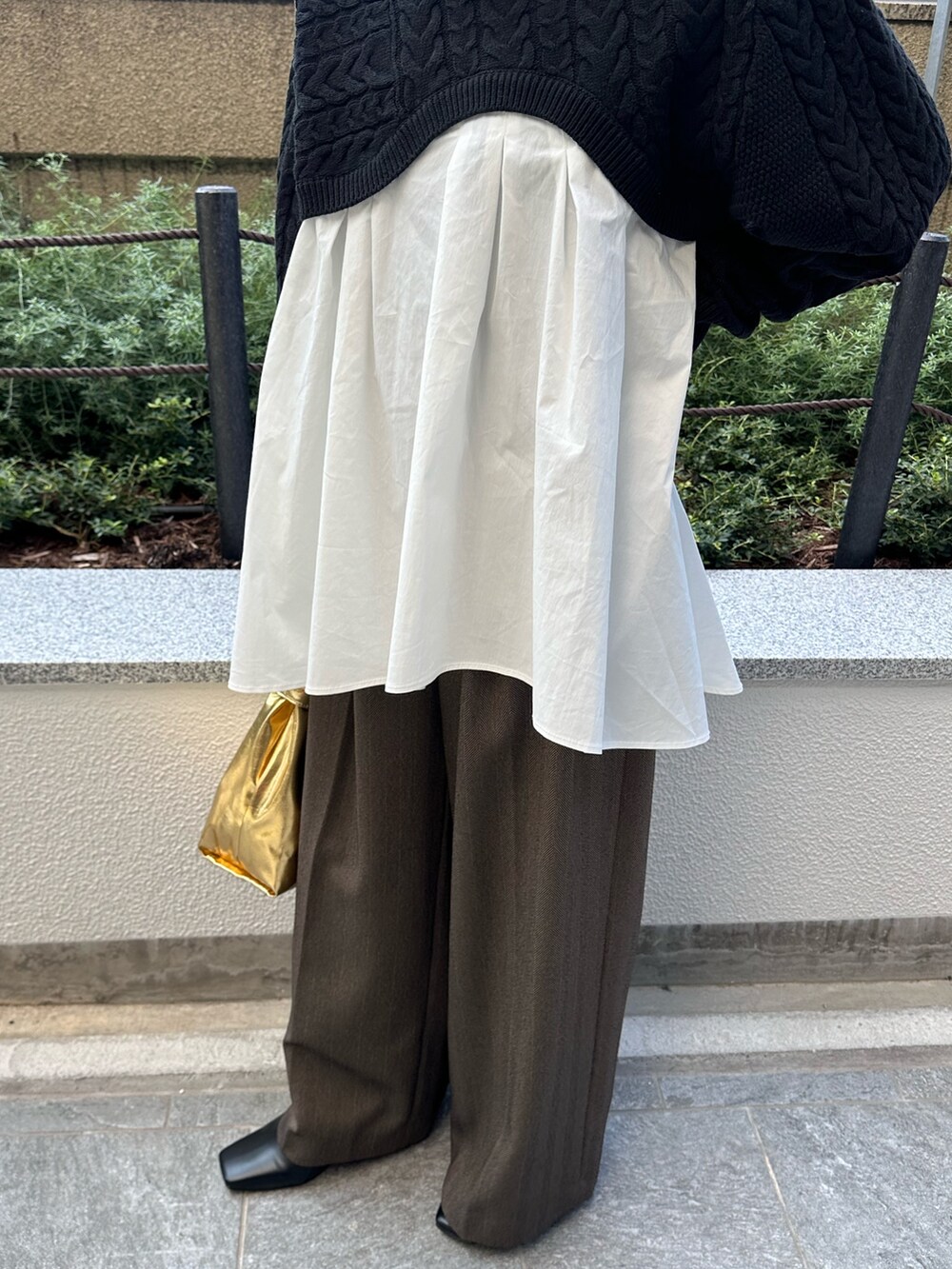 ブラック系のニット/セーター、ブラウン系のその他パンツ、ゴールド系のハンドバッグを着用したレディースの秋コーディネートの7枚目の写真