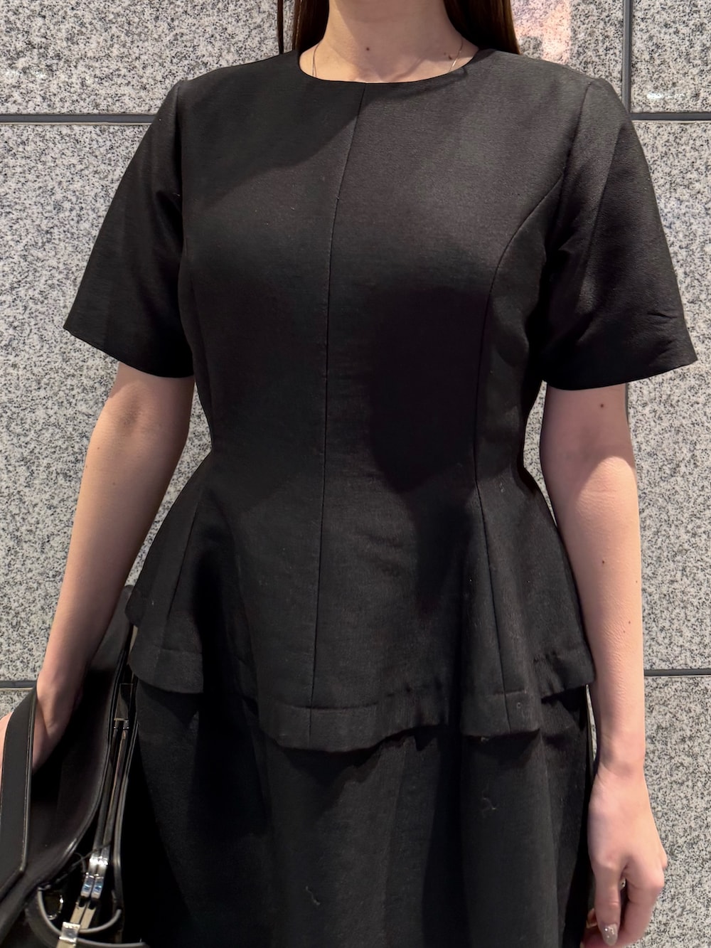 ブラック系のワンピース、ブラック系のハンドバッグを着用したレディースの冬コーディネートの6枚目の写真