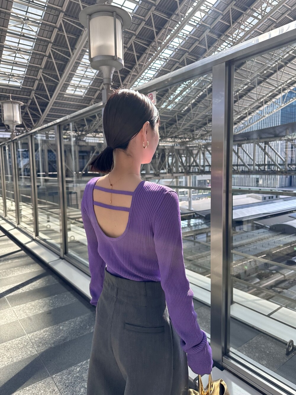 パープル系のニット/セーター、グレー系のその他パンツ、ゴールド系のハンドバッグを着用したレディースの春コーディネートの3枚目の写真