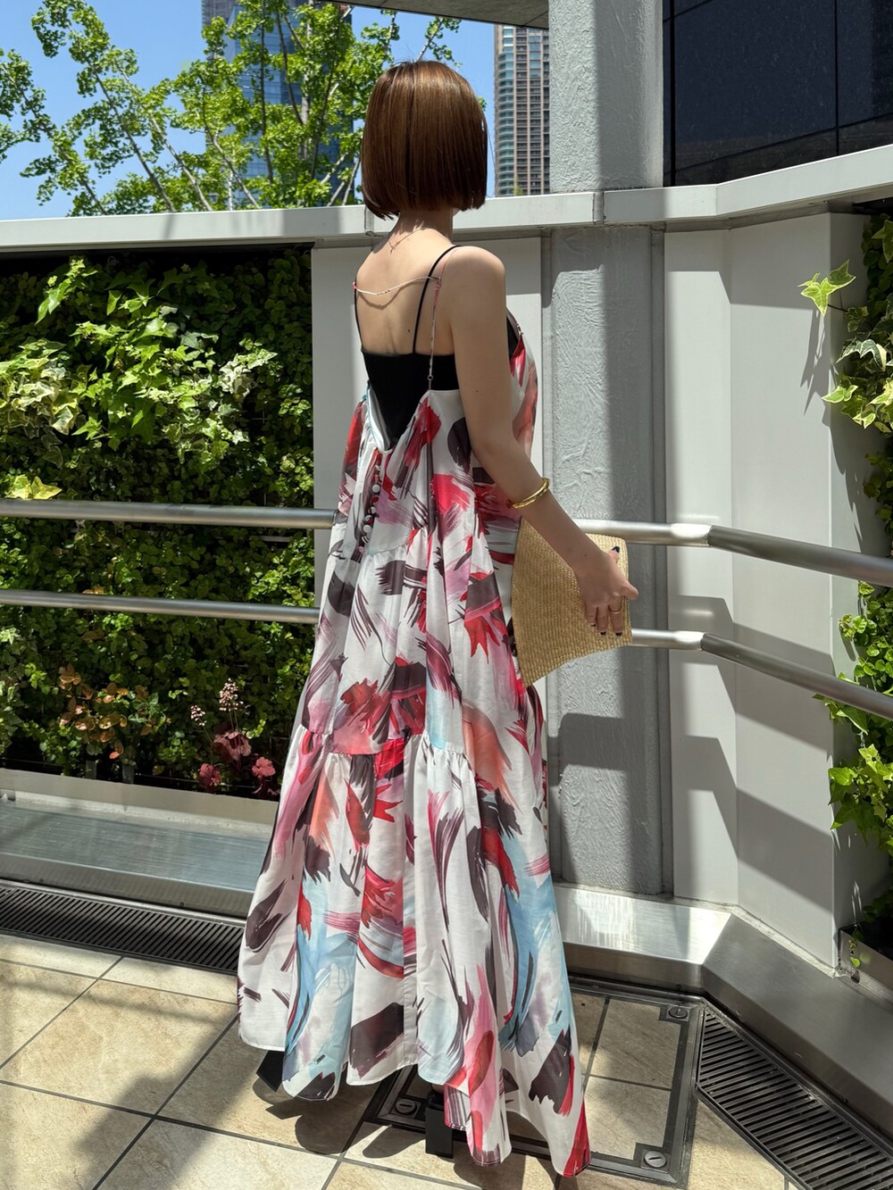 レッド系のワンピース、ブラック系のサンダル、ベージュ系のハットを着用したレディースの春コーディネートの4枚目の写真