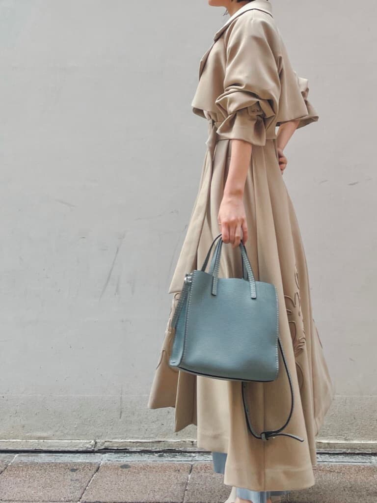 ベージュ系のトレンチコート、ブルー系のワンピース、ホワイト系のサンダルを着用したレディースの春コーディネートの3枚目の写真